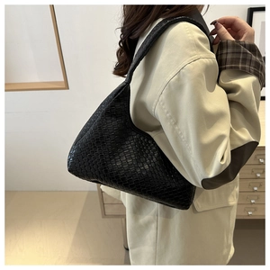 Détail du sac bandoulière en cuir tressé noir montrant la texture croisée et le fini mat