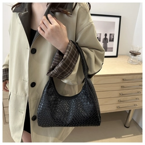 Détail du sac hobo noir à texture tressée dans un intérieur moderne et minimaliste