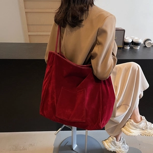 Minimalist red corduroy tote bag with large capacity and external pocket shown on shoulder