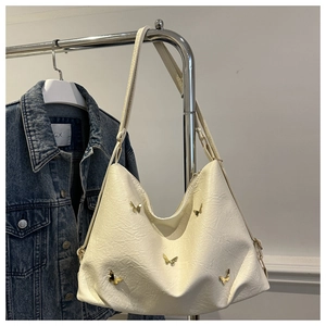 Detail of cream white pleated hobo bag with gold butterfly metal accents and PU texture