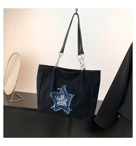 Detail of suede tote bag featuring a denim star patch and metal chain strap