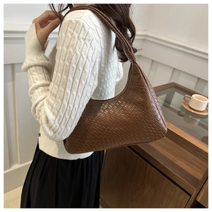 Détail de la texture en cuir tressé marron foncé d'un sac à bandoulière élégant