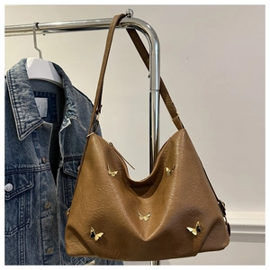 Detail of vintage brown leather tote bag with metallic butterfly accents and pleated texture