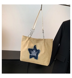 Detailed close-up of khaki faux suede tote bag with denim star patch and metal chain strap