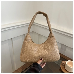 Détail de la texture tressée beige et de la finition cuir d'un grand sac porté épaule