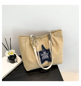 Close-up of khaki canvas tote featuring a blue denim star patch and silver metal chain