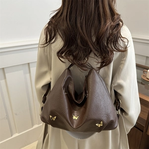 Dark brown leather multi-functional backpack with gold butterfly accents on woman in coat