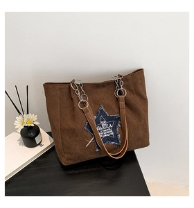 Detail of suede tote bag featuring a denim star patch and silver metal chain strap