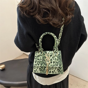 Fashionable green leopard print handbag with gold SS logo shown on black sweater