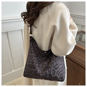 Detail of hobo shoulder bag with leopard print fabric and slim leather strap on model