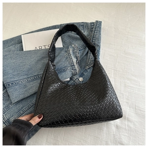 Gros plan détaillé sur la texture tressée noire de ce sac hobo chic en forme de croissant