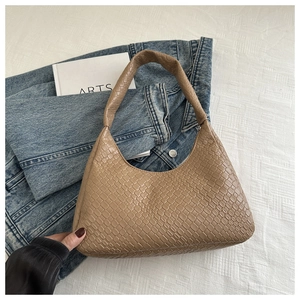Détail de la texture tressée du sac hobo beige avec sa bandoulière monobloc élégante