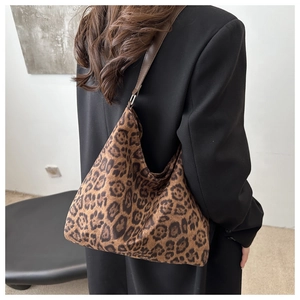 Detail view of large leopard print tote bag with brown leather strap on black blazer