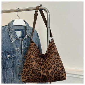 Detail of adjustable leather strap and textured leopard print fabric on a large tote bag