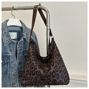 Close-up of leopard print tote bag texture with brown leather strap and metal buckle