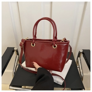 Close-up of wine red oil wax leather bucket bag with embossed lettering and gold hardware