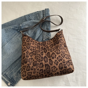 Detailed view of leopard print shoulder bag with brown strap on denim jacket background