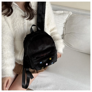 Detail of cute black plush backpack with cat face embroidery and FASHION logo