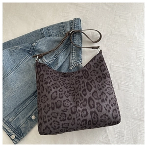 Detailed top view of leopard print tote bag with brown straps on denim jacket