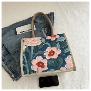 Flat lay of linen tote bag with vintage floral print beside denim jacket and book