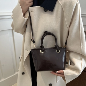 Fashionable dark brown leather bucket bag with top handles and adjustable shoulder strap