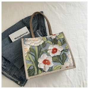 Detailed view of white floral print tote bag with brown woven rope handles and reinforced seams