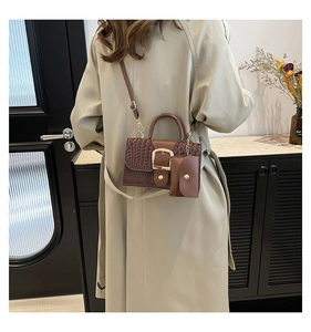 Détail de sac à main marron à texture crocodile avec boucle dorée et pochette suspendue