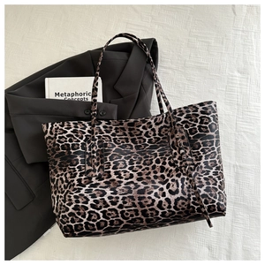 Fashionable large leopard print tote bag placed on a textured fabric background with a blazer