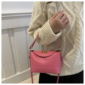 Detail of pink lychee pattern crossbody bag with golden twist lock on knit sweater