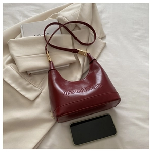 Detailed close-up of embossed lettering on the wine red leather hobo bag surface