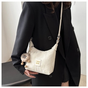 Detail of white pleated texture shoulder bag with cute brown plush lion pendant