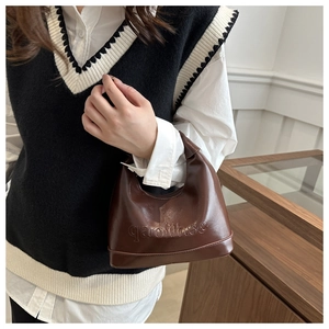 Detailed close-up of French vintage dark brown glossy shoulder bag with letter embossing