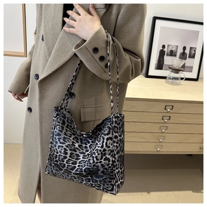 Détail d'un sac cabas léopard porté avec un manteau en laine dans un décor minimaliste