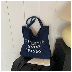Detail of blue denim tote bag with Catch the Good Things text and contrast stitching