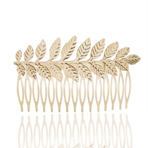 Detail of golden metal leaf hair comb with intricate olive leaf texture on white background