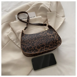 Detail view of leopard print baguette bag next to a smartphone for size reference