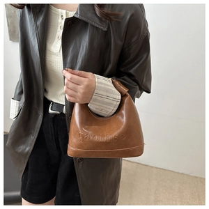 Detail of caramel brown retro shoulder bag with embossed letters and leather texture