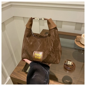 Detail of dark brown pleated textured tote bag with brand logo and silver metal hardware