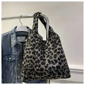 Détail d'un grand sac cabas en peluche à motif léopard suspendu dans un décor d'automne