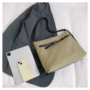 Detailed view of olive green nylon tote bag featuring brown leather strap and gold buckle