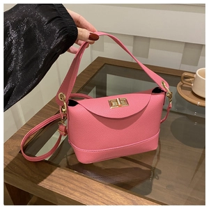Detailed shot of a pink litchi grain leather crossbody bag with a gold metal clasp