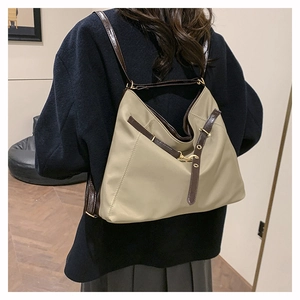 Detail view of khaki nylon tote bag with brown leather straps worn by a model
