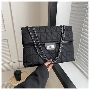 Detail of black quilted shoulder bag with silver chain strap and metal turn-lock closure