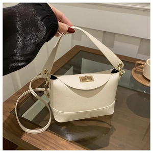 Detailed close-up of cream-colored litchi grain leather bag with gold rotating lock buckle
