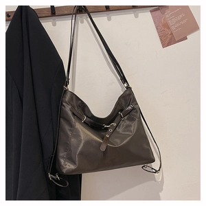 Detail of coffee nylon tote bag featuring adjustable leather straps and gold metal buckles