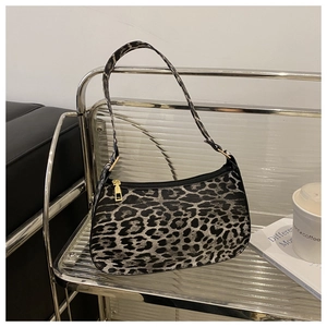 Detail of leopard print baguette bag with golden zipper on a metal display stand