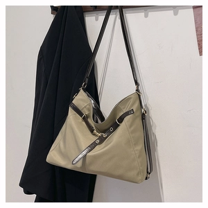 Detail of khaki nylon tote bag featuring brown leather straps and gold metal hook buckle