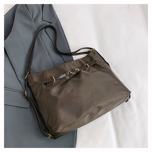 Close-up of dark brown nylon tote bag with golden metal rings and fine fabric texture
