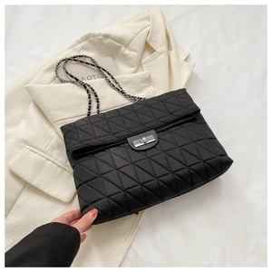 Detail of black quilted shoulder bag featuring silver chain strap and metal turn-lock