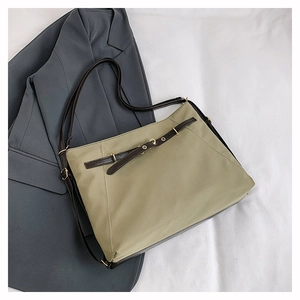 Detail of khaki nylon tote bag with dark brown leather buckle and gold hardware